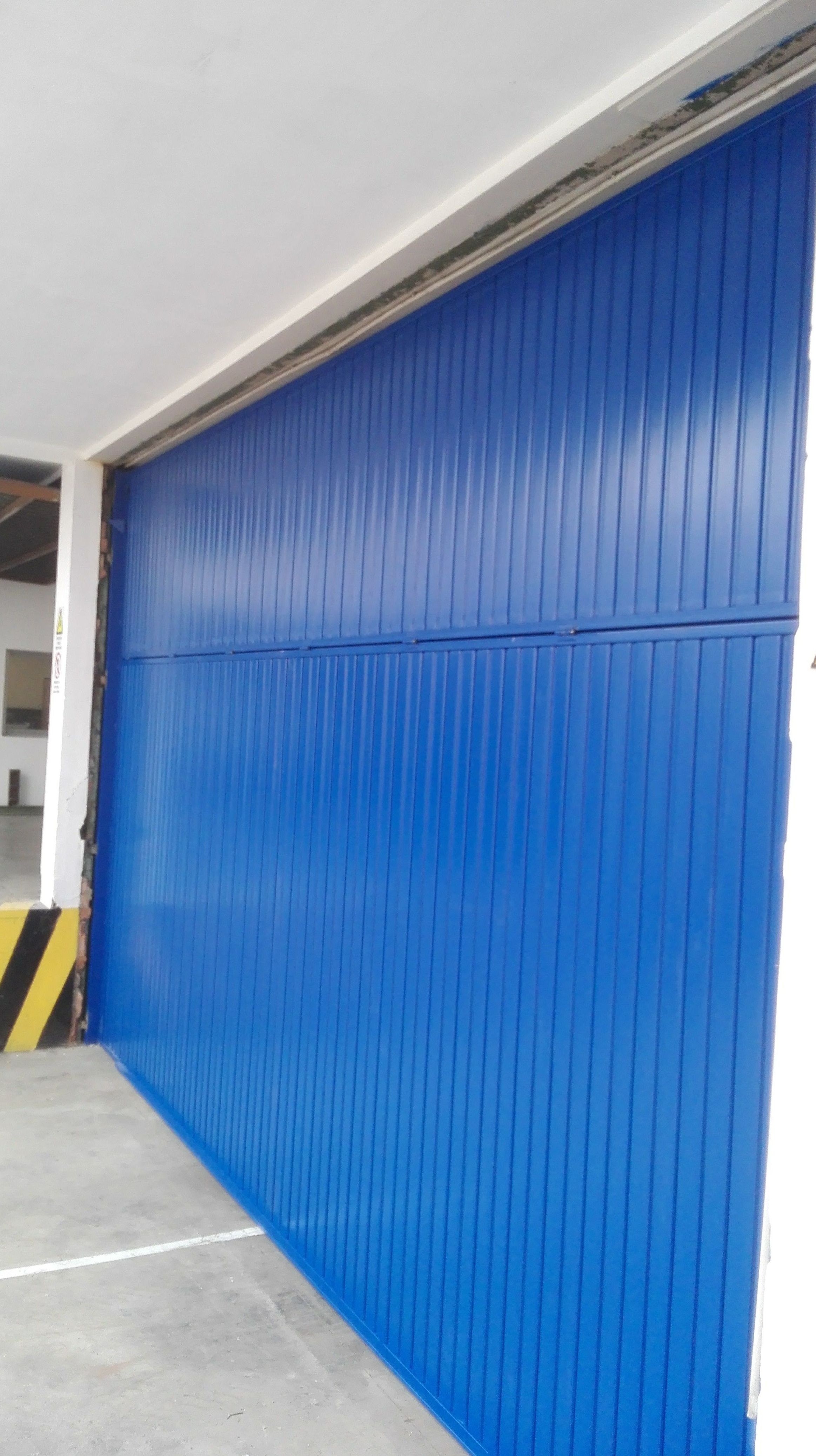 Puerta basculante de contrapesos de chapa metálica en pintura de color azul 5005 en Paterna