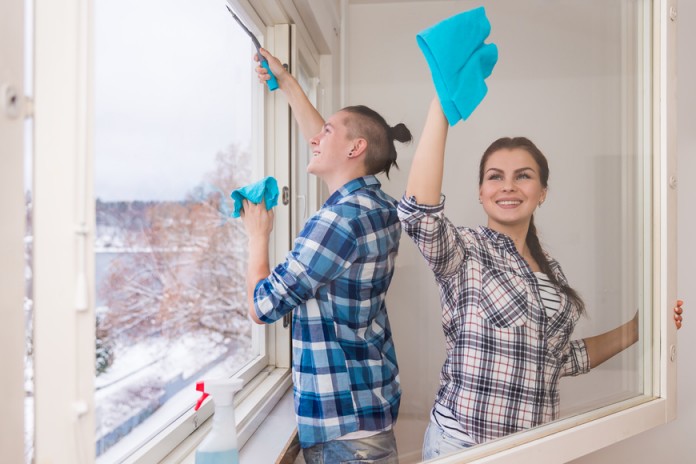 Smiling young couple cleaning windows - home improvement Sun Shine