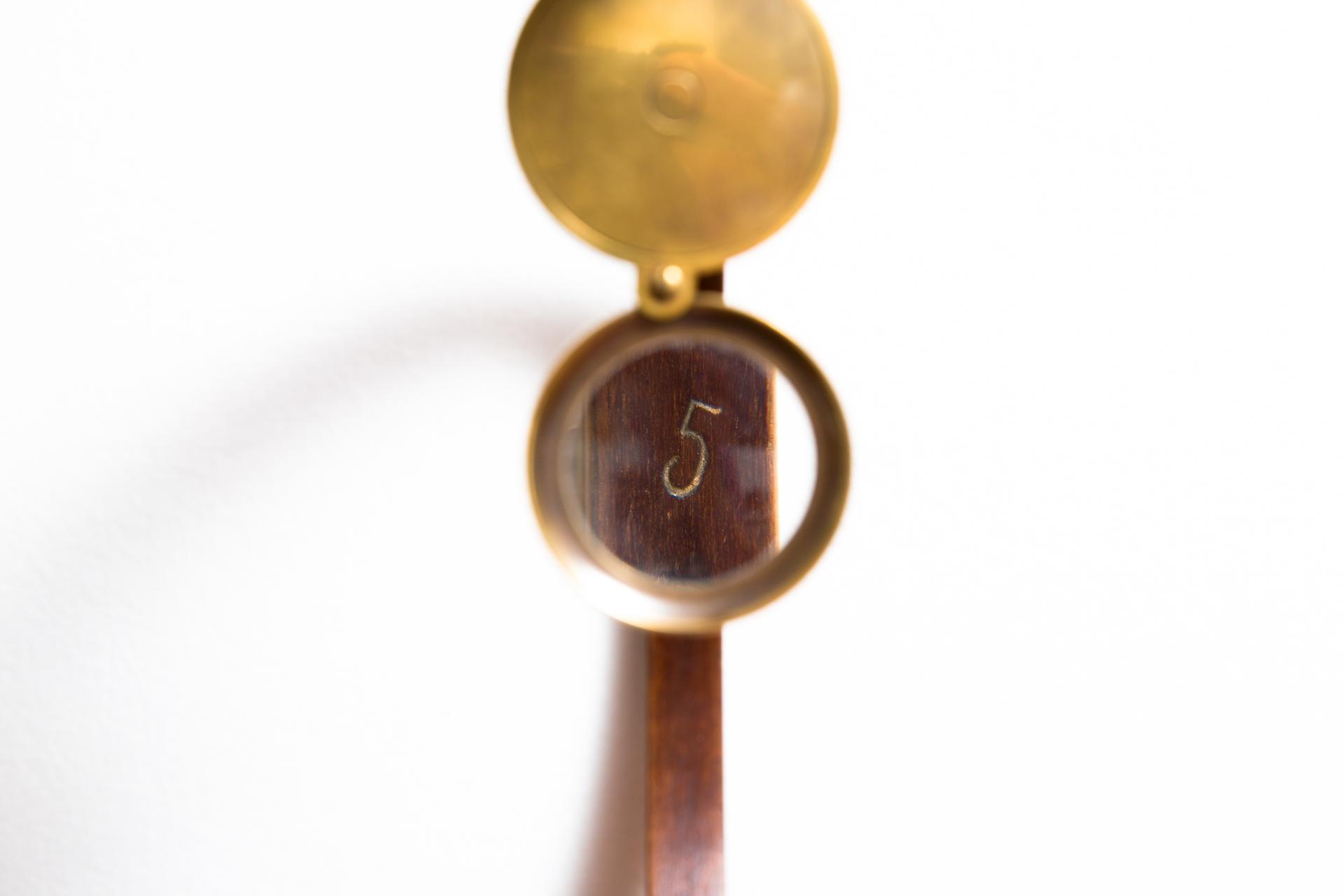 “Simetria 5”, 2012 (detalhe) madeira, lupa e número em ouro, 62 x 41 x 6 cm