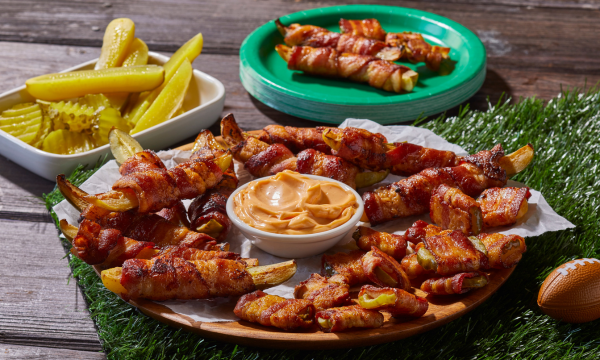 Plate of bacon wrapped spears and pickles with dip. 