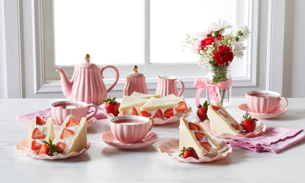 Strawberry and whipped cream sandwiches cut into rectangles. Served on pink plates with tea.