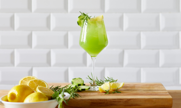 Cucumber spritz drink served in a tall glass with ice and topped with lemon and fresh thyme.