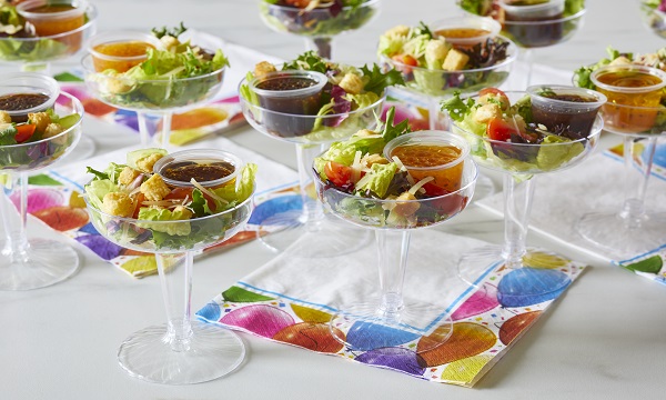 Salad cups topped with cheese, croutons, and served with dressing served in a souffle cup.