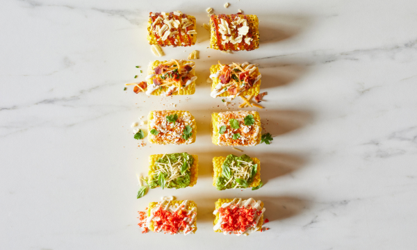 Small corn pieces topped with crushed chips and BBQ sauce, bacon bits and ranch, cheese and chili powder, pesto and parmesan cheese, and crushed hot cheeto chips.