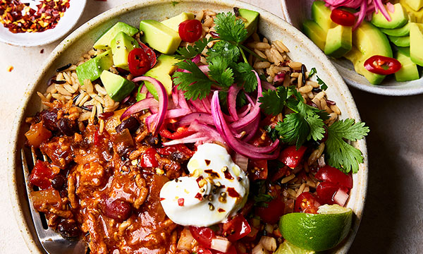 Beef & Chorizo chilli served in a bowl with fresh coriander, avocado and vibrant pickled red onions