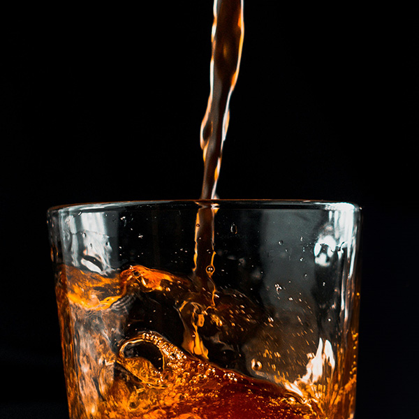 Whiskey being poured into a crystal glass on a black background