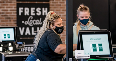 employee assisting customer with self-checkout