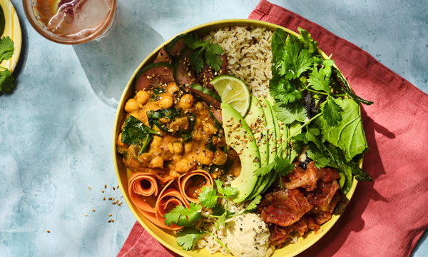 A buddha Bowl created by the happy pear, filled with chick peas, brown rice, advacado, cucumber, lime, mixed leaves