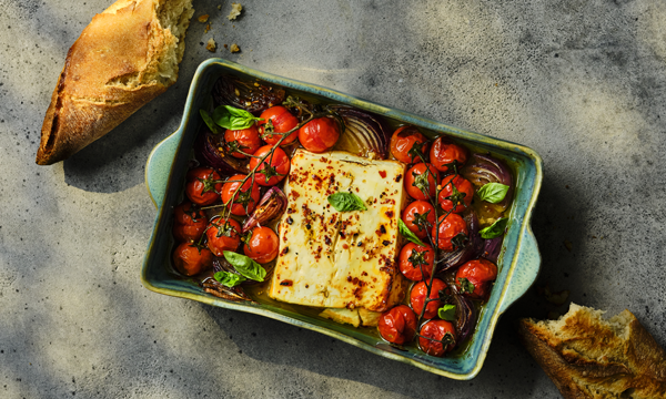 Baked Feta cheese in a dish with ripe tomatoes