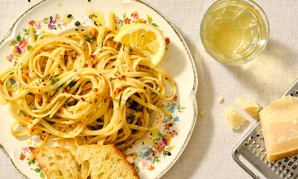 A floral plate of spaghetti cooked with lemon, garlic and parsley, served with garlic bread