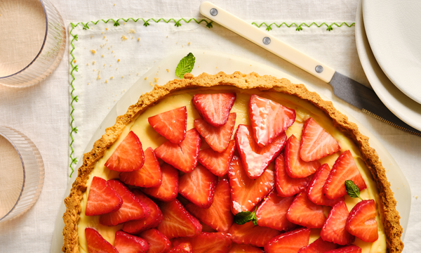 A pastry tart, filled with strawberry and apricot jam, topped with fresh strawberries