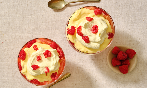 2 small dishes, will with strawberry jelly, fresh strawberries and raspberries, cream and custard