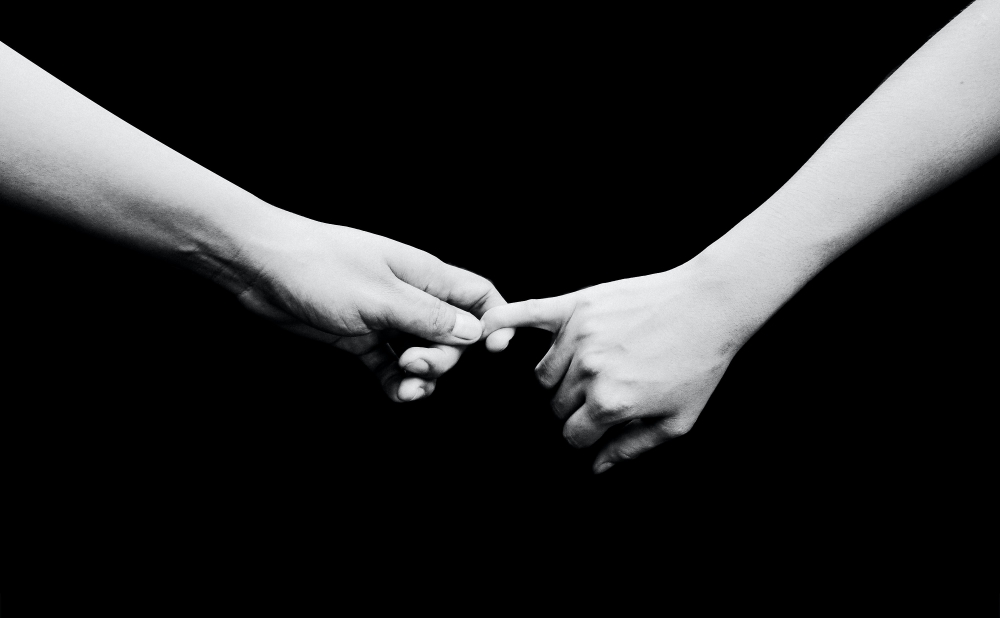 two hands held together in front of a black background