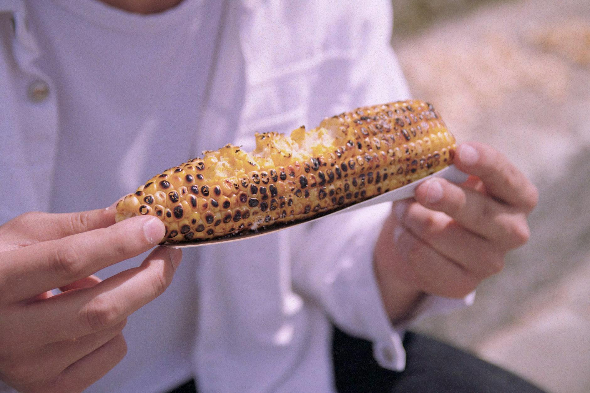 Close-up of a man eating grilled corn on the cob in Istanbul, Türkiye.