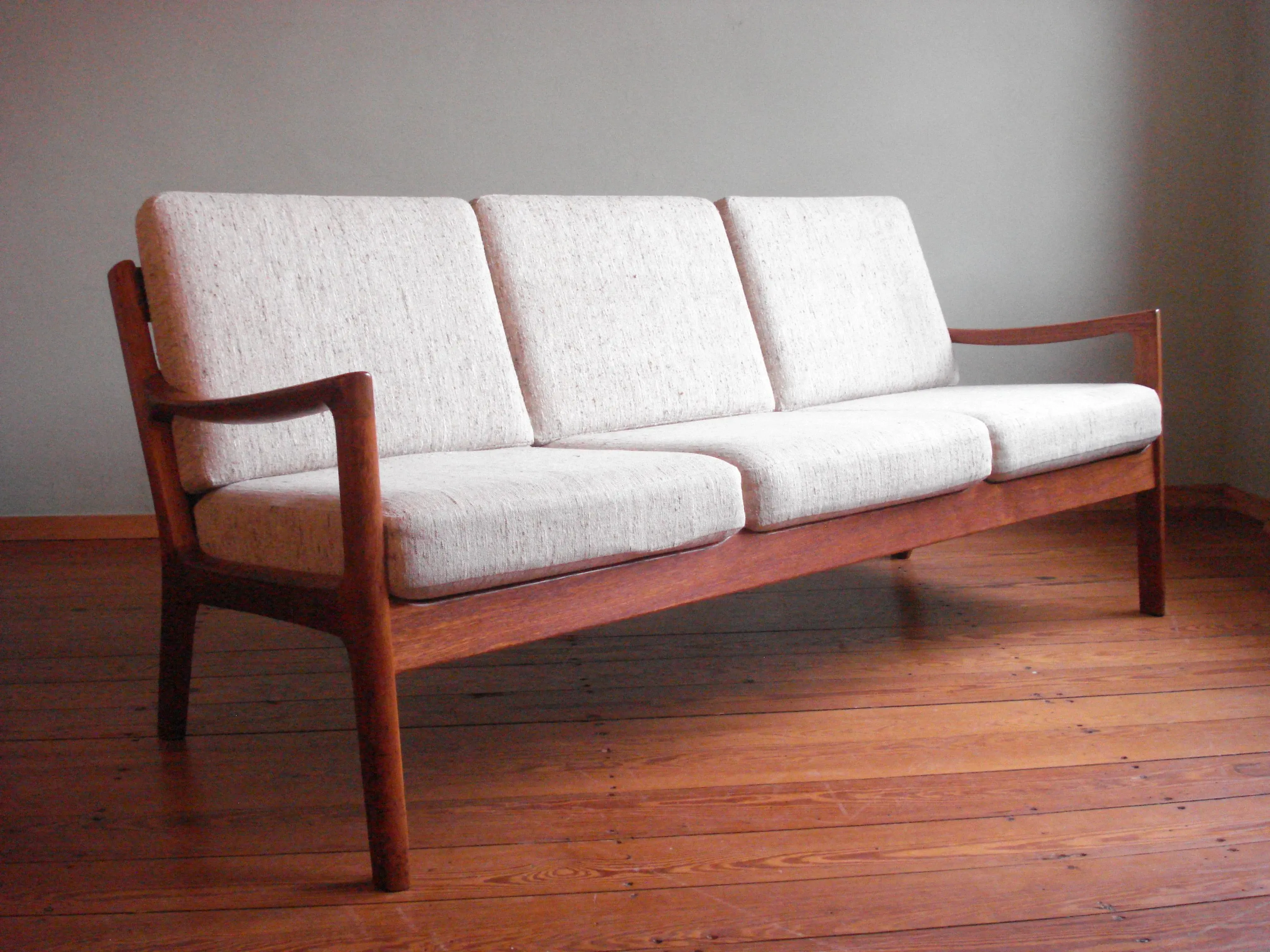 Vintage 3 seater wooden sofa with cream cushions, image