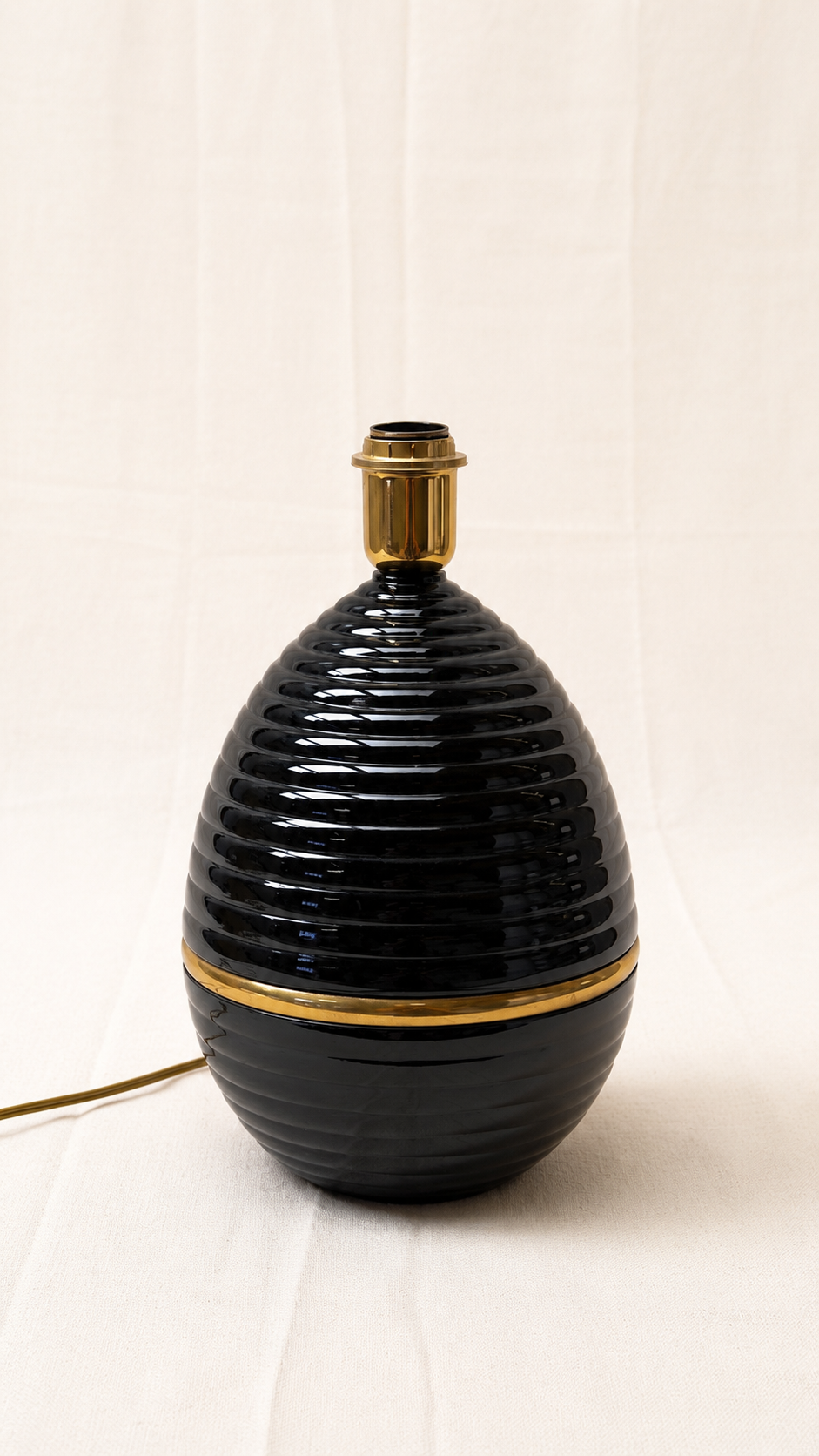 A black ribbed ceramic table lamp with brass fittings and a gilt band.