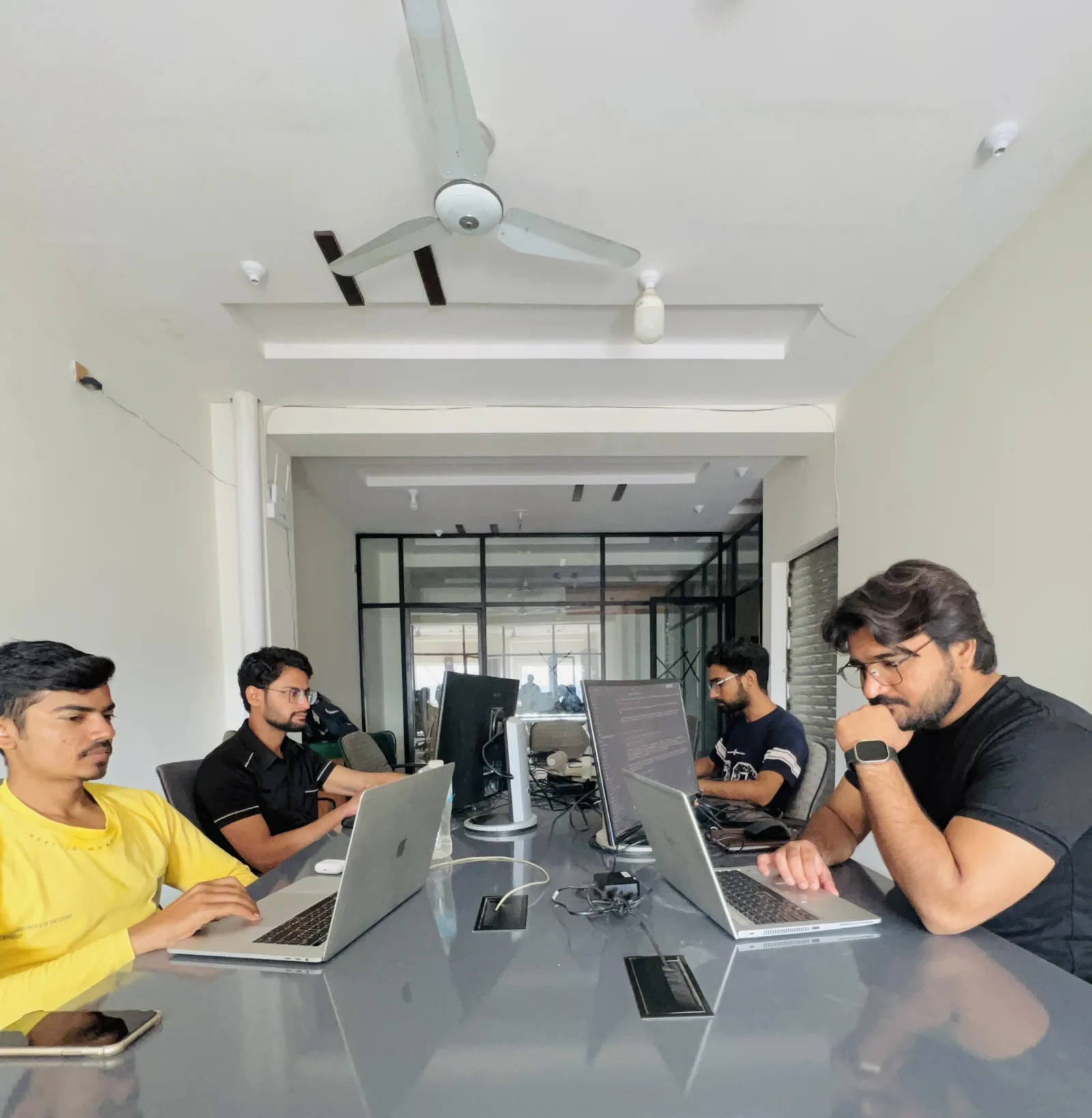 Engineers working along a shared desk in a sunlit office