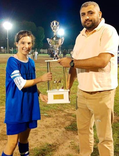 La capitana del Club Rivadavia recibe el trofeo de manos del titular del Departamento de Fútbol Femenino de la Liga, David Forconi Bearzotti.