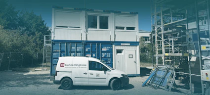 ConnectingCase Serviceauto vor Bürocontainer auf einer Baustelle mit Baustellengerüst