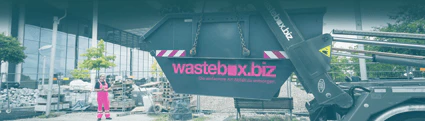 wastebox.biz Bauschutt Container wird vor einem Lagerplatz mit einem Gebäude im Hintergrund abgeladen
