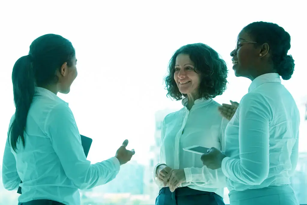 Profissionais conversam de forma colaborativa, representando comunicação empática e humanizada no ambiente corporativo.