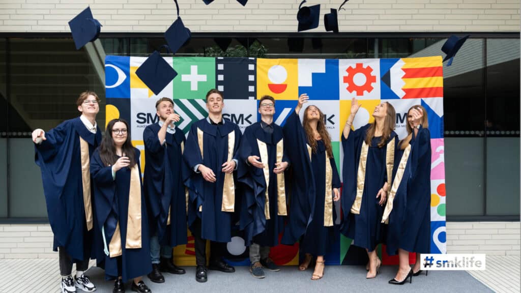 Diverse university graduates celebrating at graduation ceremony in academic regalia.