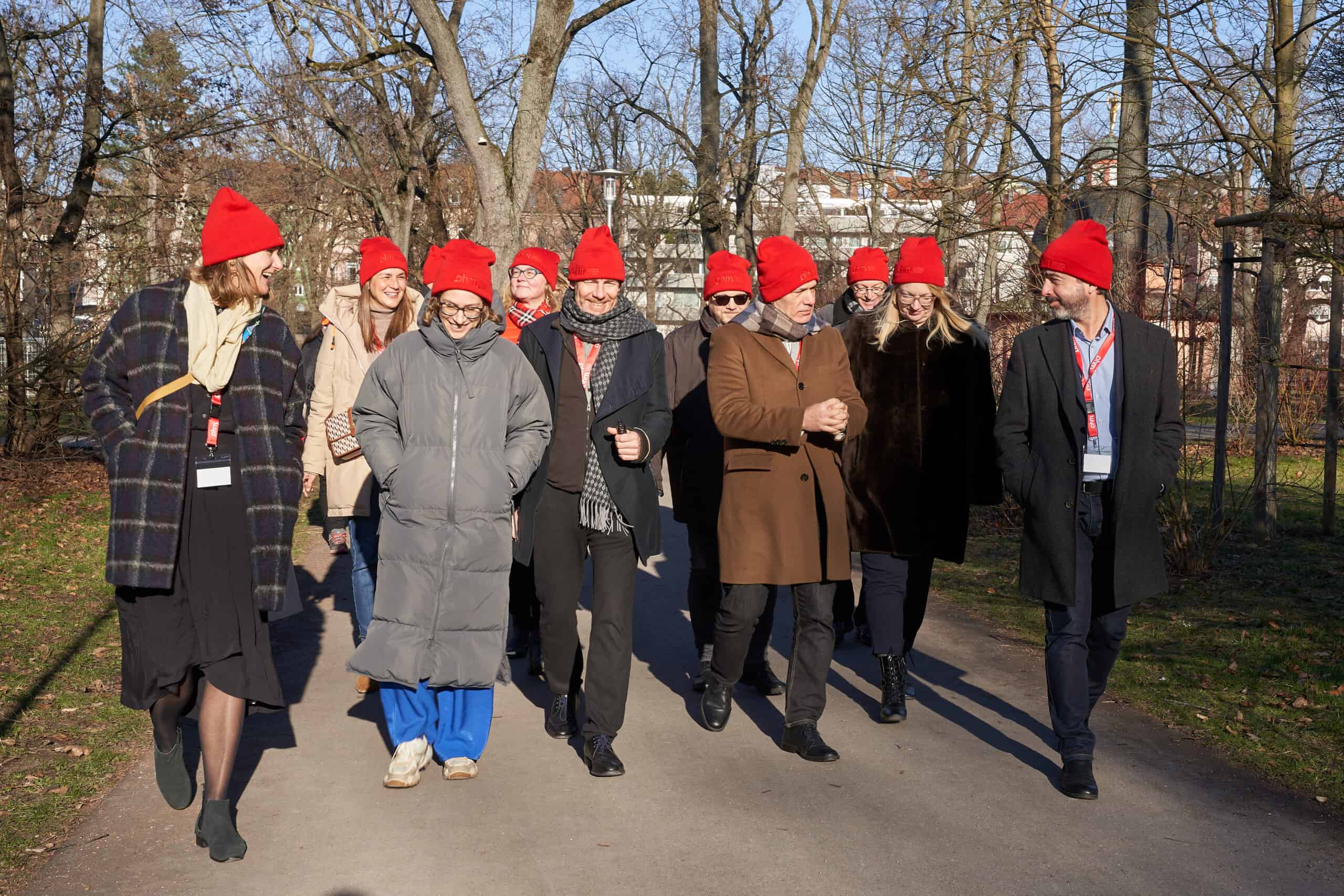 DIVERSE university group wearing red hats, walking outdoors in cold weather.