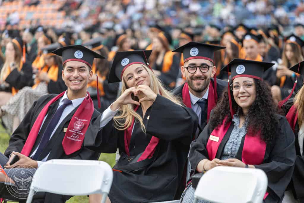 Smiling diverse students in caps and gowns celebrating graduation at university event.