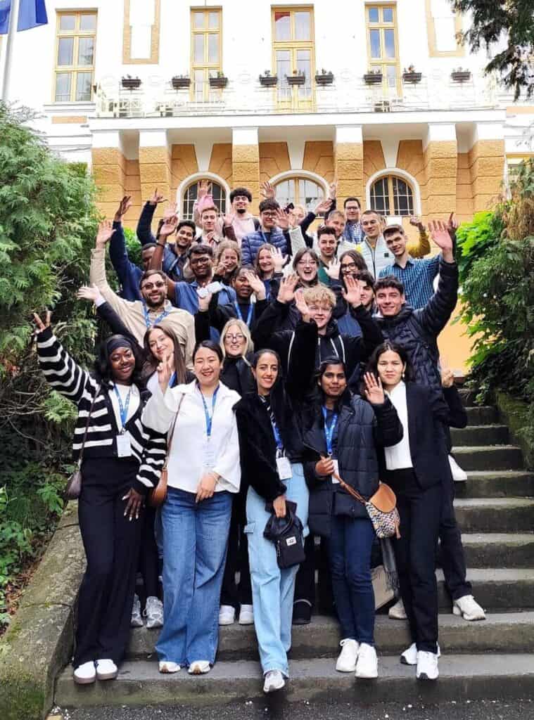 Diverse group of students outside a historic building, celebrating international collaboration and inclusion at DIVERSE university event.