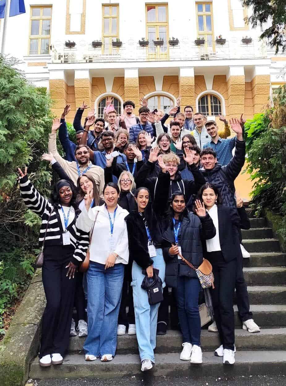 Diverse group of students outside a historic building, celebrating international collaboration and inclusion at DIVERSE university event.