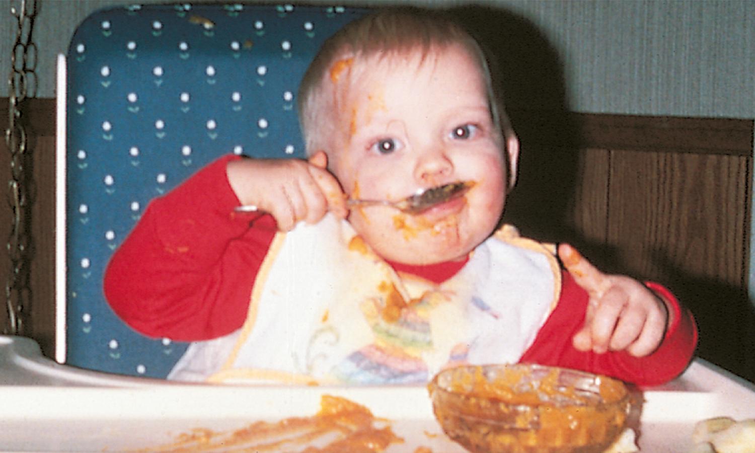 Fig. 3.18, Independent feeding. A 15-month-old child employs fine motor skills to use a spoon independently.