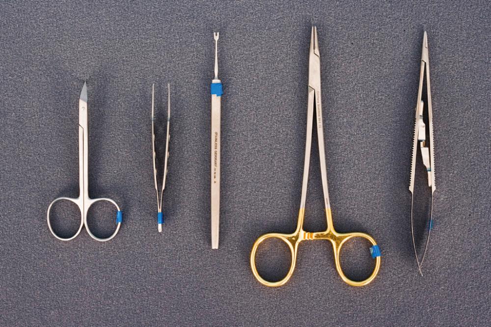 Fig. 19.3, A basic set of fine instruments for facial soft tissue repair, including needle drivers, forceps, scissors, and skin hooks.