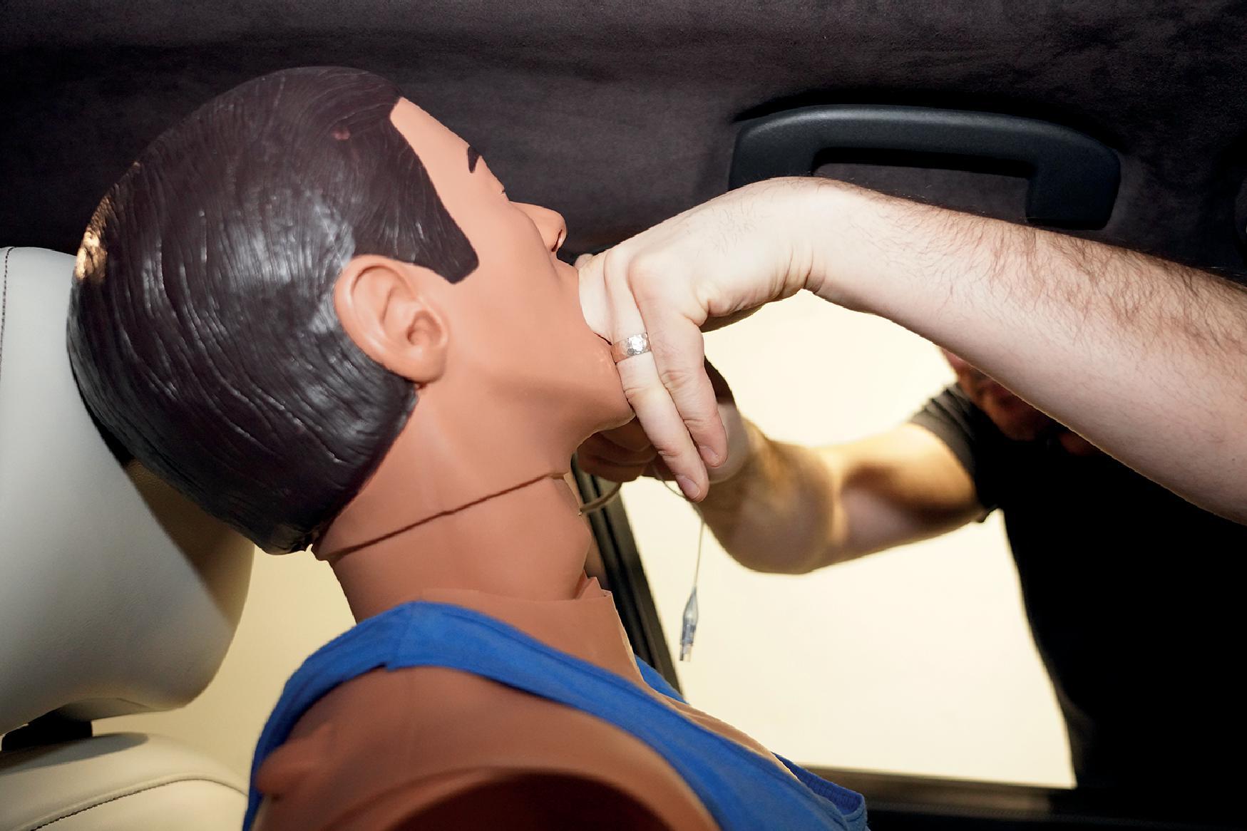 Fig. 21.4, Digital intubation of a trapped driver on the left side of the vehicle. The left hand of the clinician palpates the epiglottis while the right hand delivers the ETT.