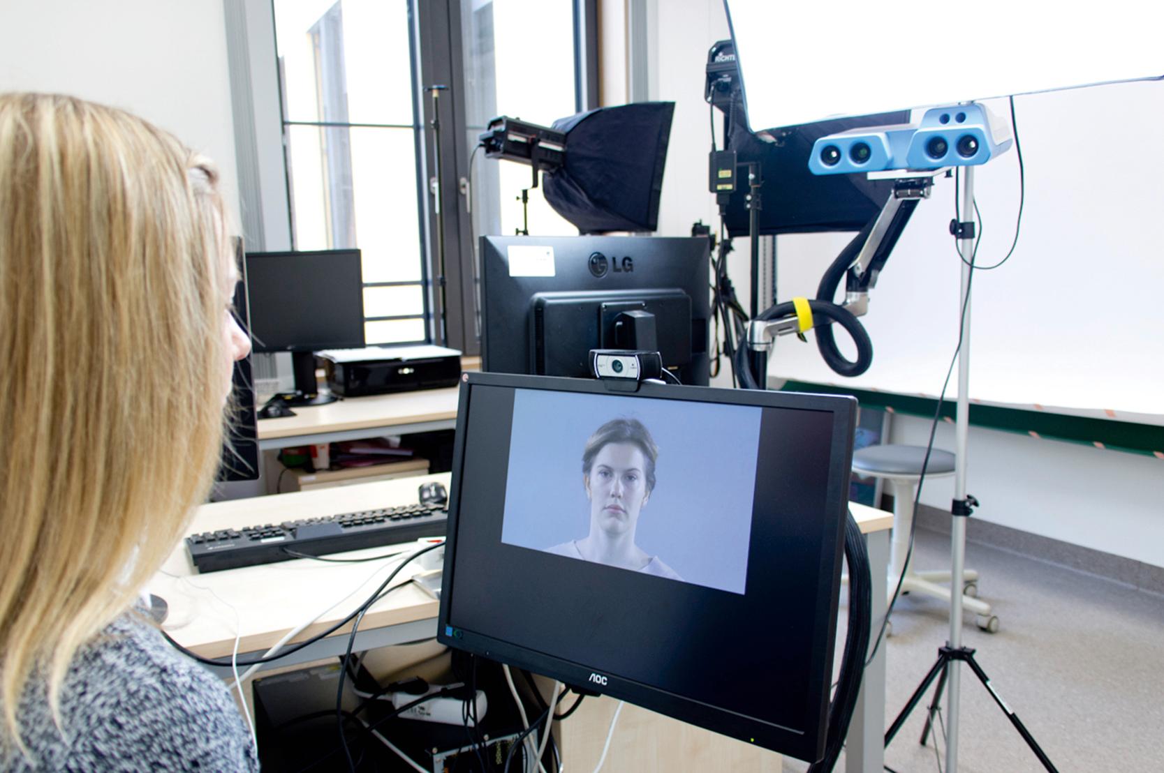 Fig. 8.1, Setting for two- (gray and black webcam) and three-dimensional (blue IRESTRA Sensor, Fraunhofer Institute for Applied Optics and Precision Engineering IOF, Jena, Germany) video recording with light source and screen. The patient is given an instruction video so as to minimize the personal influence of a photographer and get videos as standardized as possible.