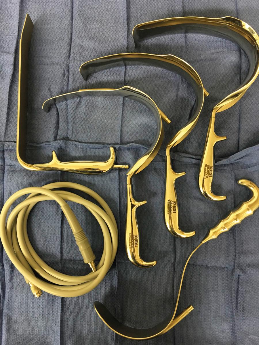 FIGURE 180.2, A set of lighted pelvic retractors greatly facilitates reoperative pelvic surgery. Clockwise from upper left : straight-blade retractor; narrow, medium, and wide curved deep pelvic retractors; Deaver retractor.