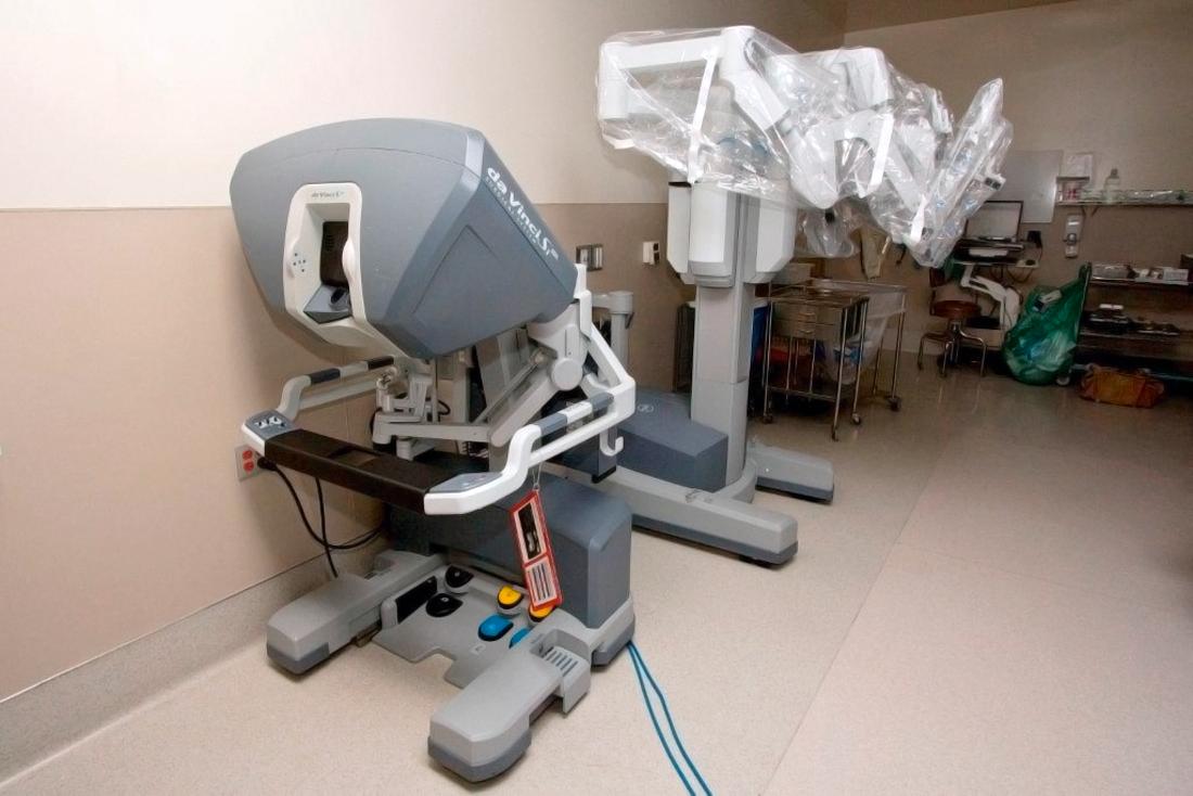 FIG. 118.3, The robotic system is kept away from the operating table until trocars are in place and ready for docking. The surgeon’s console is located away from the operating table.