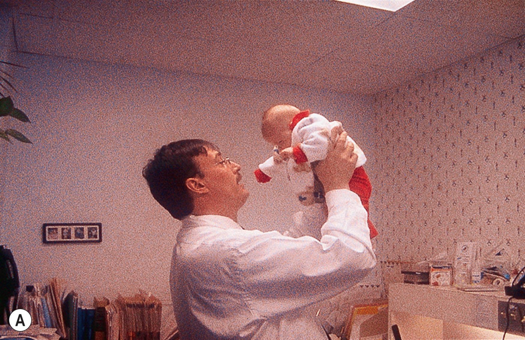 Fig. 91.8, Clinical evaluation of infant eye movements. The child is rotated in the examiner's arms in the vertical (A) and horizontal (B) planes to test the vestibulo-ocular, optokinetic, and saccadic systems. (C) An optokinetic drum is rotated close to the child in the vertical direction to assess visual fixation and saccadic and optokinetic functions.