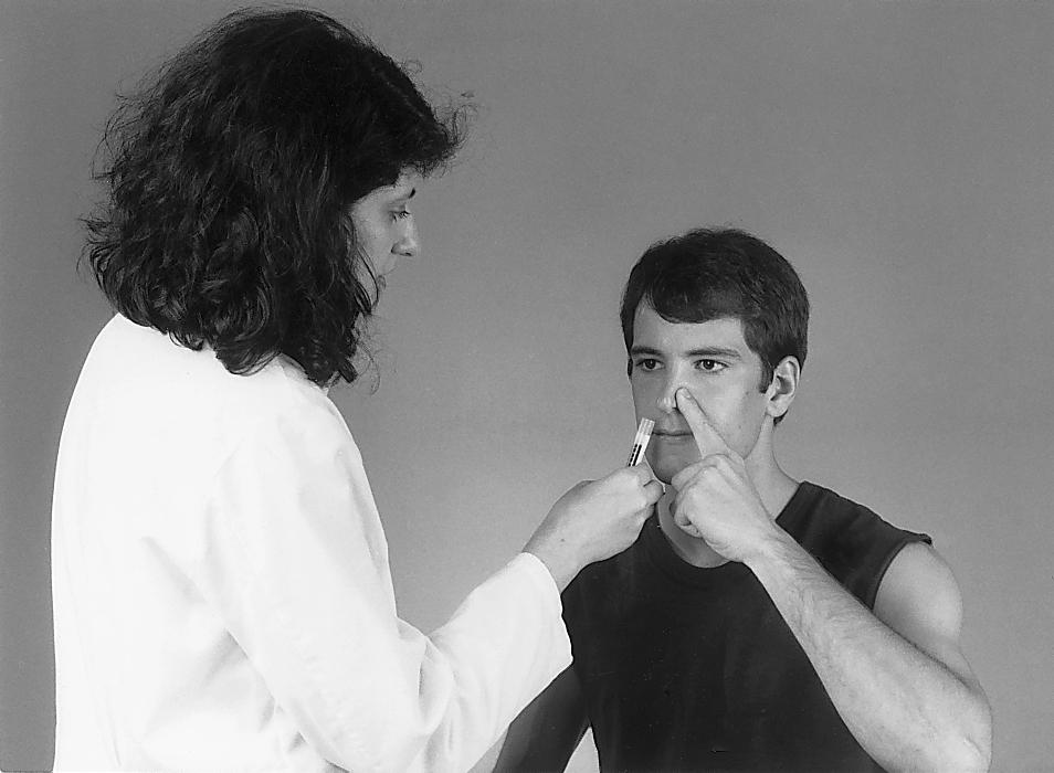 Fig. 33.4, Testing of the sense of smell (olfaction). The patient presses one nostril closed, and the open nostril is exposed to an aromatic substance.