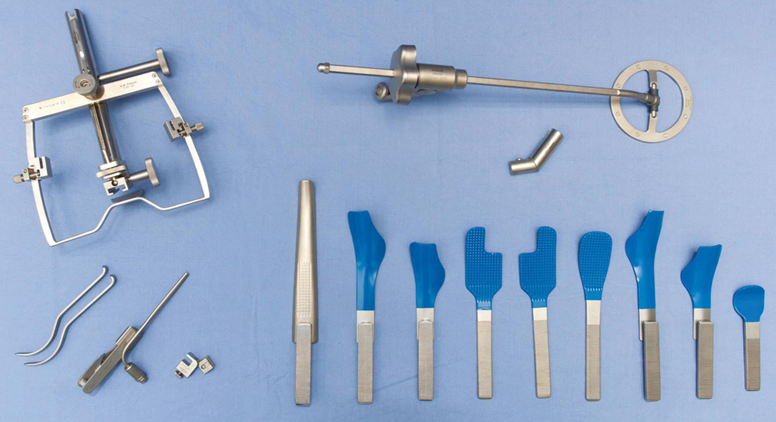 Fig. 97.11, Feyh-Kastenbauer retractor (upper left) ; suspension arm (upper right) ; cheek retractors and clip-on light source (lower left) ; and a variety of tongue blades (lower middle and right) .