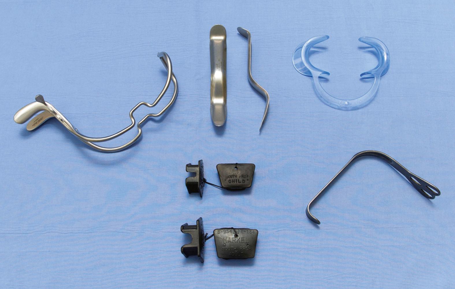 Fig. 97.9, Jennings mouth prop ( upper left ); Minnesota retractor (upper middle) ; plastic cheek retractors (upper right) ; adult and child rubber bite blocks, demonstrating both sides of the block (lower middle) ; and a sweetheart retractor (lower right) .