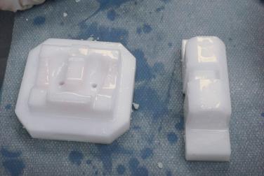 FIGURE 33A.4, Molds for the femoral component. The base mold (left) supports the articular surface of the implant, and the bone surface mold (right) contours the bone-implant surface and compresses the cement into the runners. Both have been coated with mineral oil.