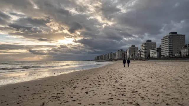 Wandelaars op een breed strand aan de Belgische kust in het najaar