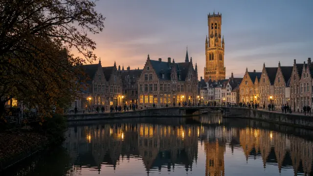 Historische Vlaamse stad met gracht en belfort bij valavond