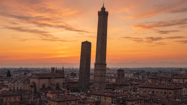 De twee torens van Bologna boven de rode daken bij zonsondergang