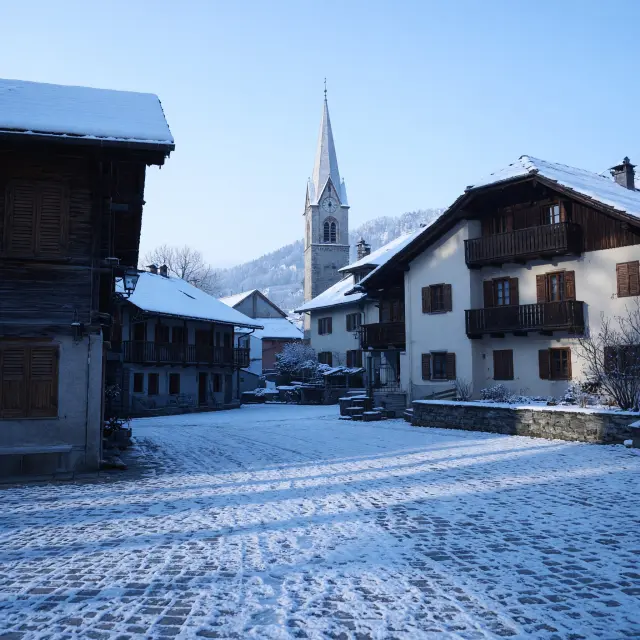 Rustig bergdorp Campitello di Fassa met houten chalets en besneeuwde Dolomietentoppen op de achtergrond
