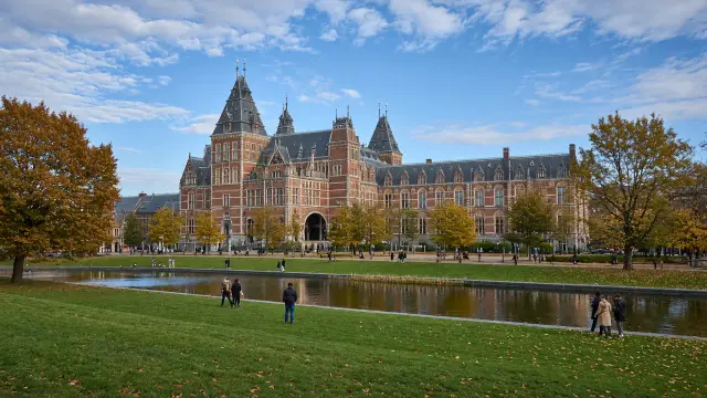 Het Museumplein in Amsterdam met het Rijksmuseum op de achtergrond en wandelaars op het grasveld