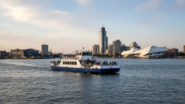 Een pont vaart over het IJ naar Amsterdam-Noord met fietsers en voetgangers aan boord