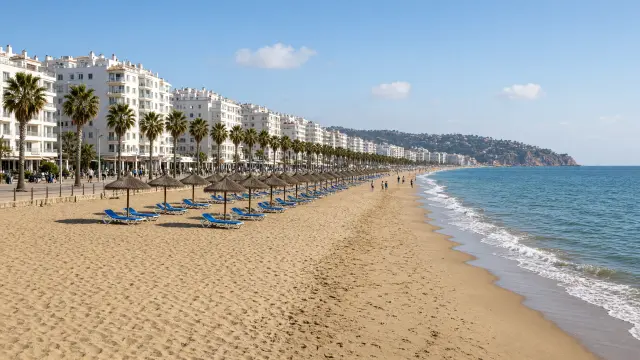 Breed zandstrand met parasols en een boulevard met palmbomen in Torremolinos