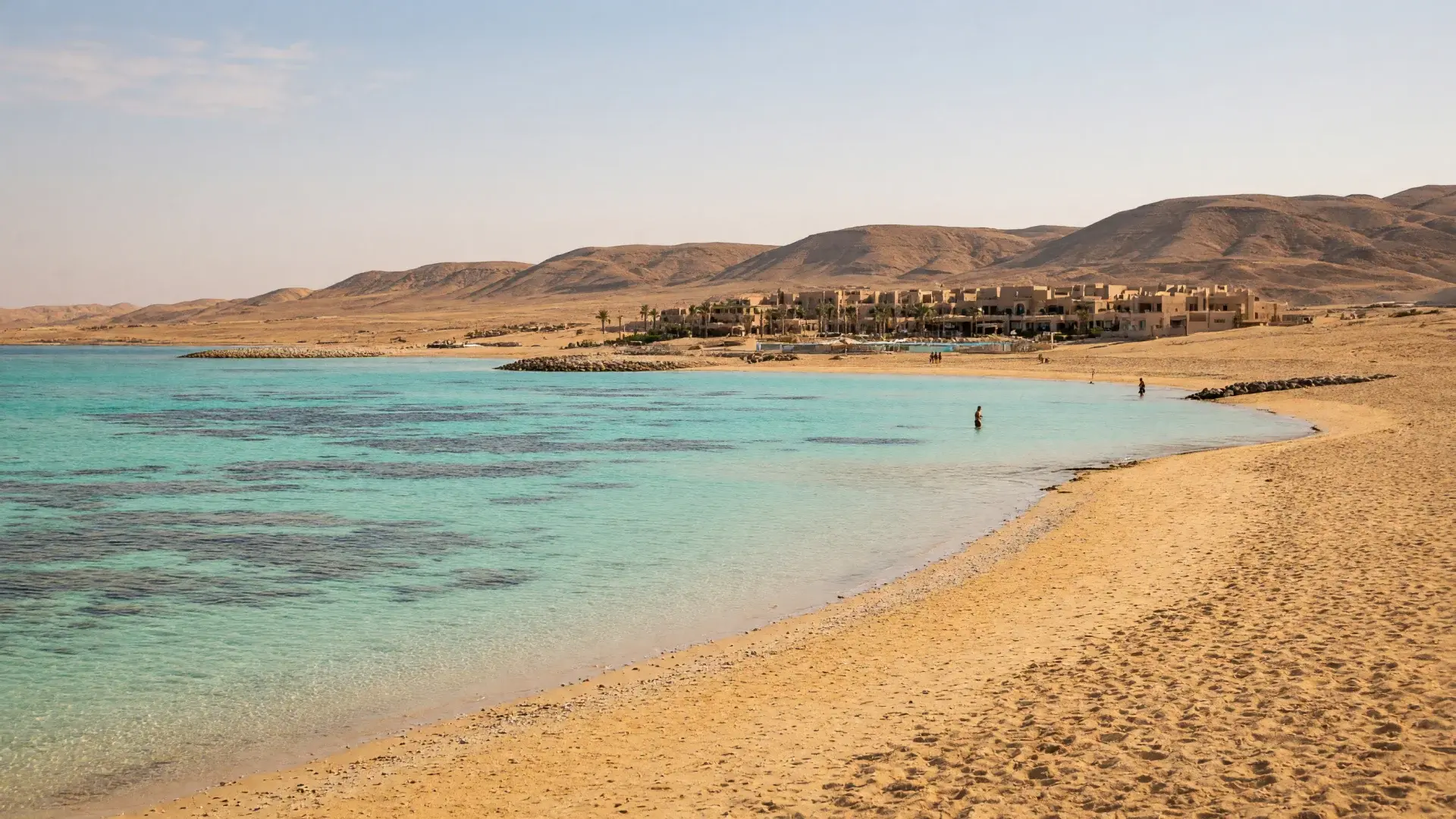 Strand met turquoise lagune en woestijnheuvels bij Marsa Alam