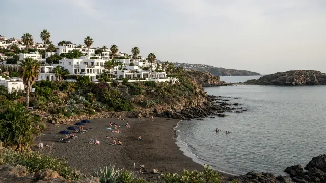 Kleine baai met donker zandstrand, palmbomen en witte vakantieappartementen in San Agustín op Gran Canaria